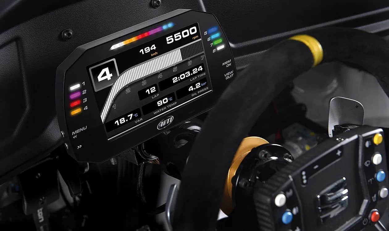 An AiM dash display showing Safe2Race information behind a race car steering wheel