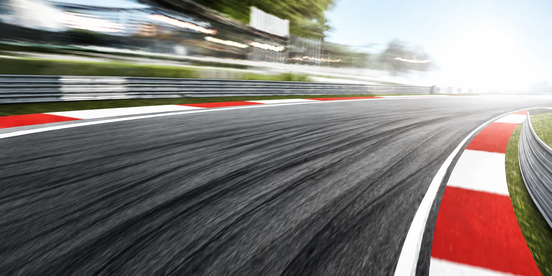 A race track with red and white kerbs, blurred at speed